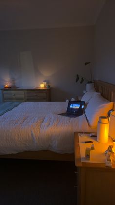 a laptop computer sitting on top of a bed next to two night stands and lamps