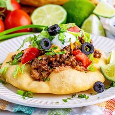 a taco salad on a tortilla topped with sour cream and black olives