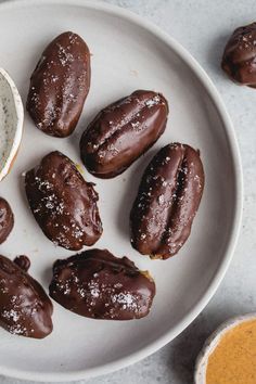 chocolate covered doughnuts on a plate next to a bowl of powdered sugar