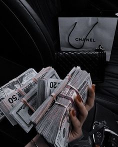 a woman holding cash in her hand while sitting in the back seat of a car