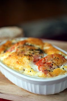 a casserole dish with ham and cheese in it on a wooden cutting board