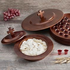 three wooden bowls with buttons and crosses in them on a table next to some grapes