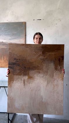 a woman holding up a large piece of art