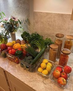 an assortment of fresh fruits and vegetables on a counter top in a kitchen with marble counterstop