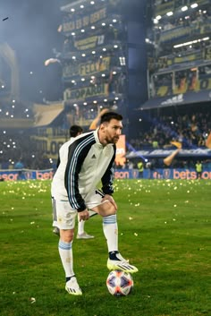 the soccer player is ready to kick the ball on the field in front of an audience