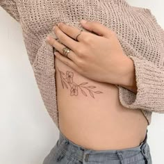 a woman's stomach with a flower tattoo on her left side ribcage