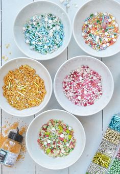 six white bowls filled with different colored sprinkles