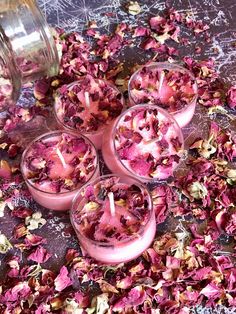 pink candles are sitting in small glass bowls with petals scattered on the floor next to them