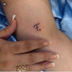 a woman's foot with a small tattoo on her left ankle and the word f in cursive font