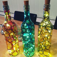 three bottles with lights in them sitting on a table