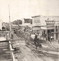 an old black and white photo of people walking down the street in front of buildings