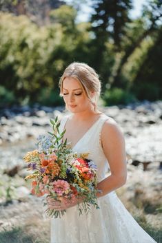 a woman holding a bouquet of flowers in her hands and looking down at the ground