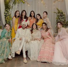 a group of people sitting next to each other in front of a white wall with lights