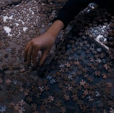 a person reaching for a piece of jigsaw puzzle on the ground with their hand