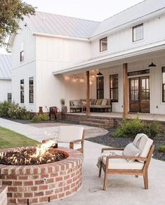 a fire pit sitting in the middle of a yard next to a white house and lawn furniture