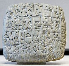 an ancient stone with writing on it and symbols in the middle, sitting on a white surface