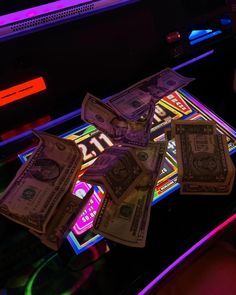 several stacks of money sitting on top of a neon lit table in front of a tv