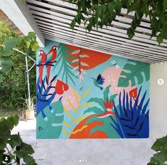 a painting on the side of a building with tropical plants and birds painted on it