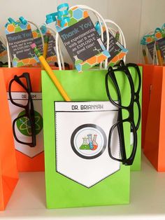 an orange and green paper bag with some black glasses on it, sitting next to other bags