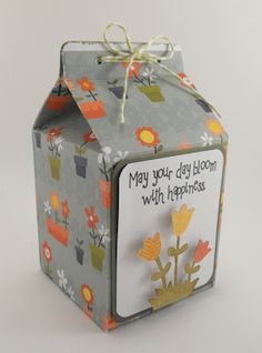 a small gift box with flowers on it and a card attached to the top that says, may your day bloom with happiness