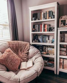 a chair with a book on it in front of a bookshelf filled with books