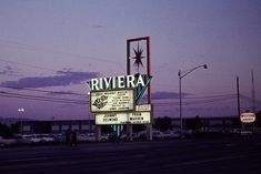 the riviera theater sign is lit up at night with cars parked on the street