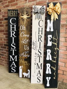 three wooden christmas signs on the side of a brick wall, one with a bow