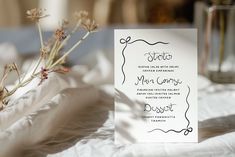 a white card sitting on top of a table next to a vase filled with flowers