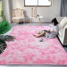 a woman sitting on the floor in front of a pink area rug that looks like she is reading