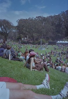 many people are sitting on the grass at a park