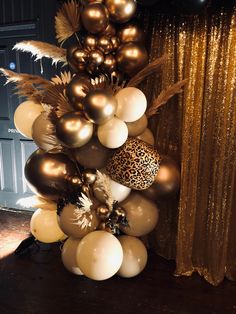 a bunch of balloons that are in the shape of a tower with gold and white decorations