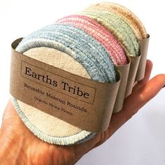 a hand holding four rolls of earth's tribe reusable material rounds in different colors