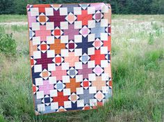 a patchwork quilt hanging in the grass