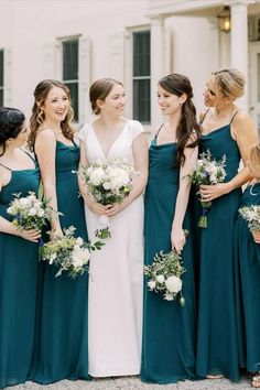 a group of women standing next to each other wearing dresses and holding bouquets in their hands