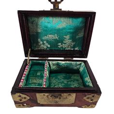 an open wooden box with green and gold designs on the inside, sitting on a white surface