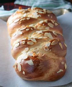 a loaf of bread sitting on top of a piece of paper covered in almonds