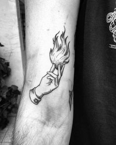 a black and white photo of a man's arm with a burning hand tattoo on it