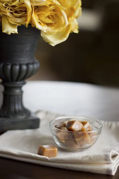 a glass bowl filled with marshmallows on top of a table next to a flower vase