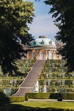 a large building with stairs leading up to it in the middle of trees and bushes