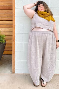 a woman leaning against a wall with her hands on her head and wearing a yellow scarf around her neck