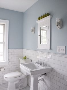 an image of a bathroom with blue walls and white tile on the wall, in front of a mirror