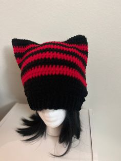 a knitted black and red cat hat on top of a mannequin head