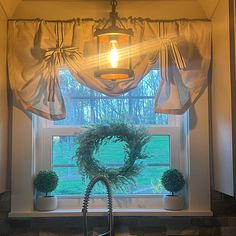 a light hanging from the ceiling over a window in a kitchen with potted plants