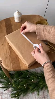 a person using a wii remote to play a video game on a wooden table next to a christmas tree