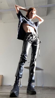 a man in leather pants and boots posing for the camera with his hands on his hips