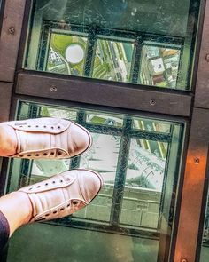 a person standing on top of a glass floor with their feet in the air and looking down