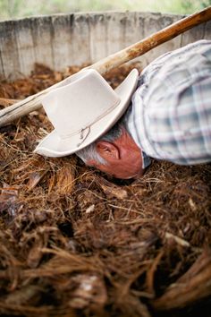 an old man wearing a cowboy hat is digging in the ground