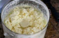 a blender filled with white food on top of a granite counter next to a knife