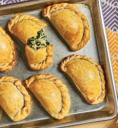 six pastries on a baking sheet with spinach and other toppings in them