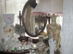 a table topped with lots of clutter next to a large mirror and lampshade